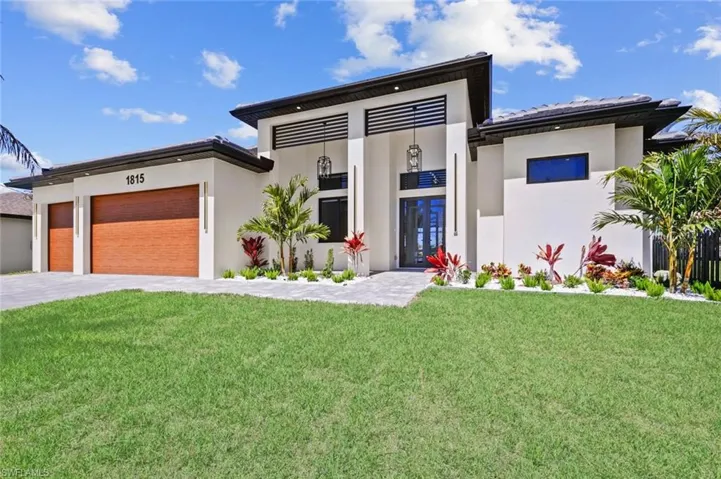 View of front of home featuring a front yard, a garage, driveway, and stucco siding