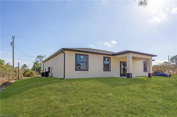 Rear view of property featuring stucco siding, a lawn, a patio, and a ceiling fan
