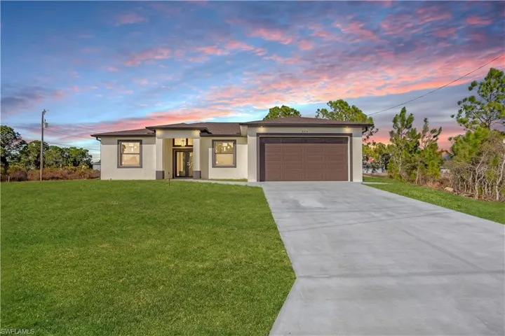 Prairie-style home with stucco siding, a lawn, and concrete driveway