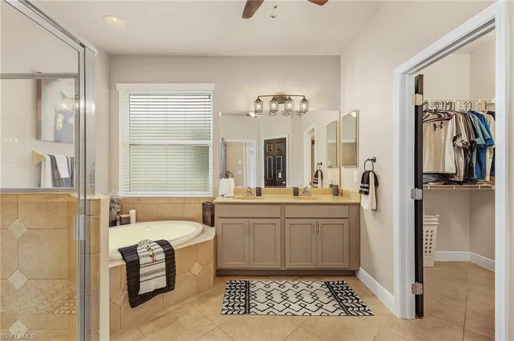 Bathroom with tile patterned flooring, vanity, separate shower and tub, and ceiling fan