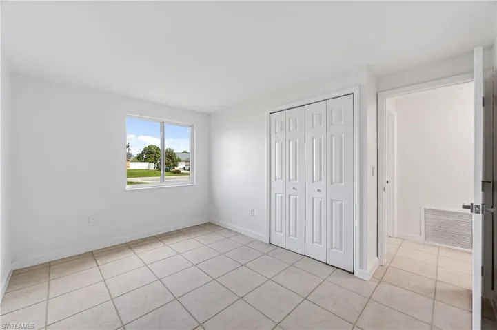 Unfurnished bedroom with a closet and light tile patterned flooring