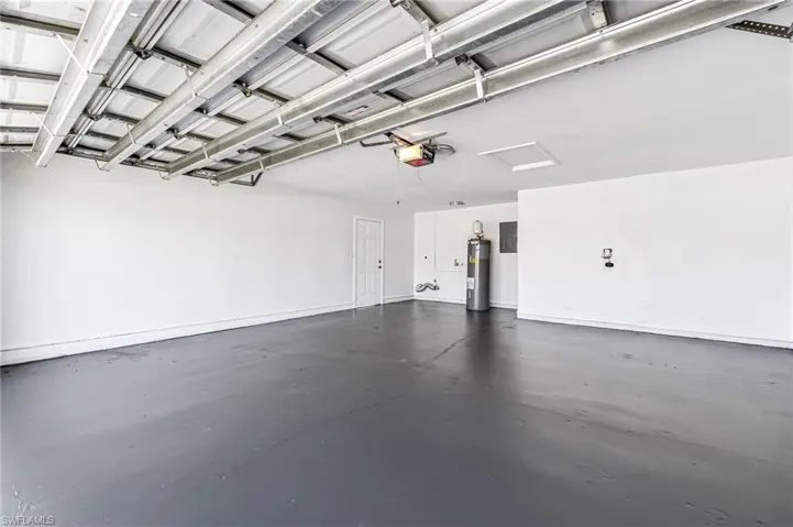 Garage with electric panel, water heater, and a garage door opener