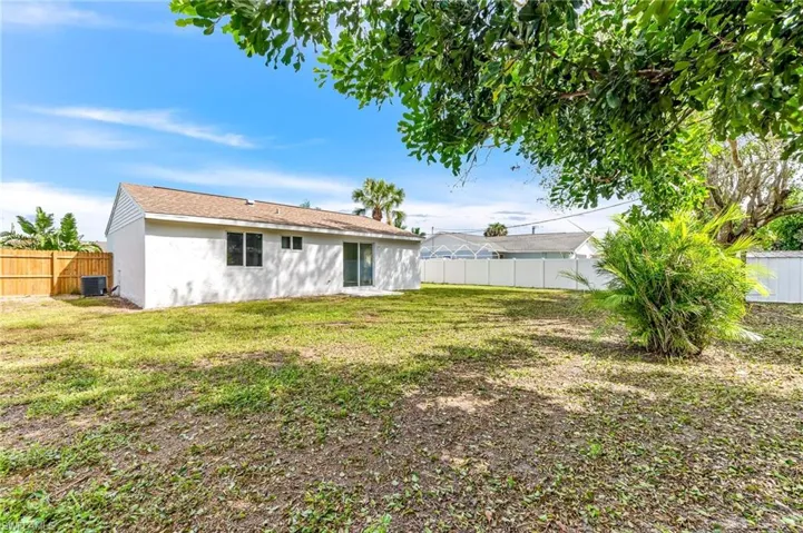 Rear view of property with central AC unit and a lawn