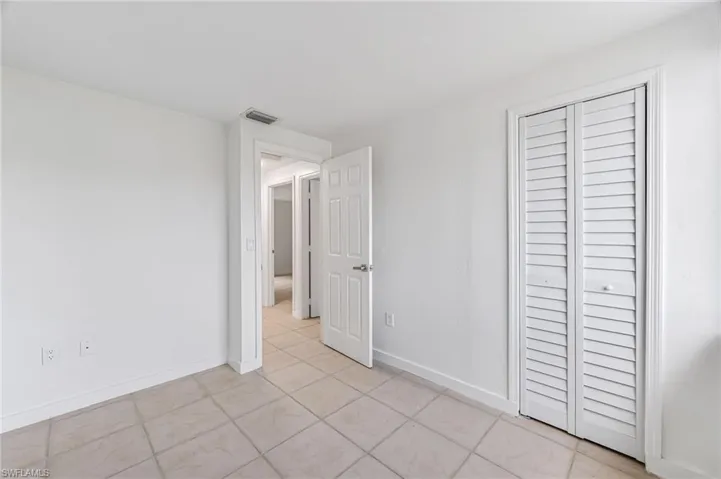 Unfurnished bedroom with a closet and light tile patterned flooring