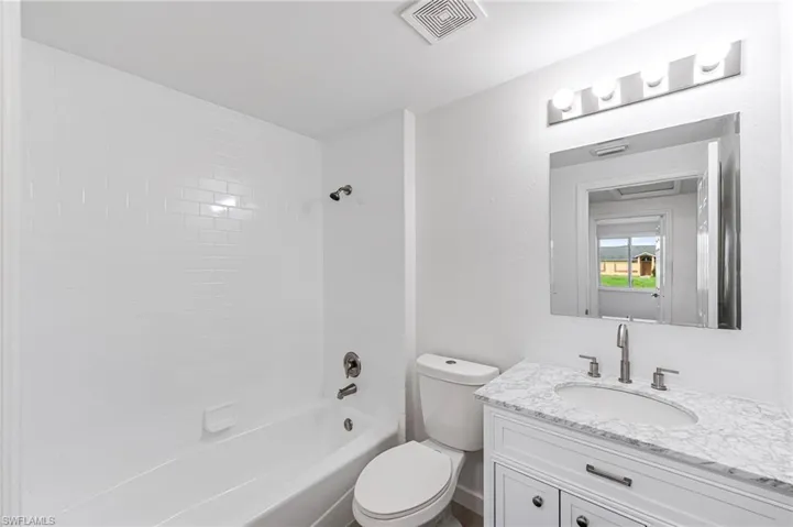 Full bathroom with washtub / shower combination, vanity, and toilet