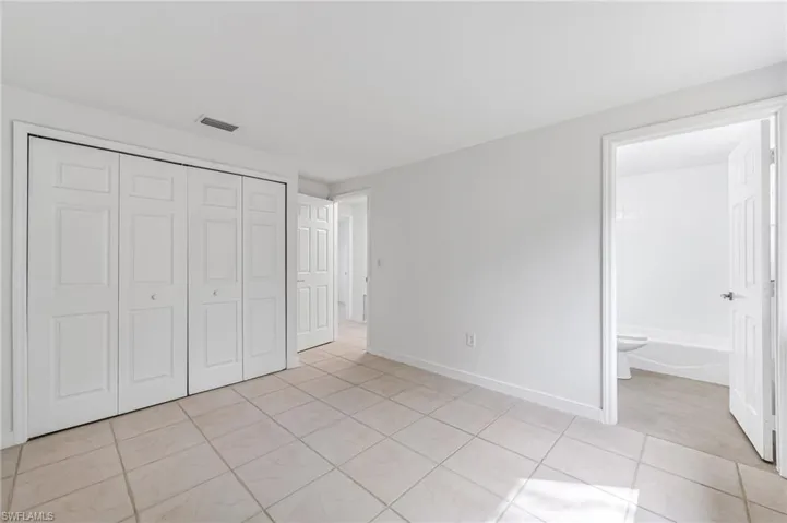 Unfurnished bedroom with a closet, light tile patterned floors, and ensuite bath