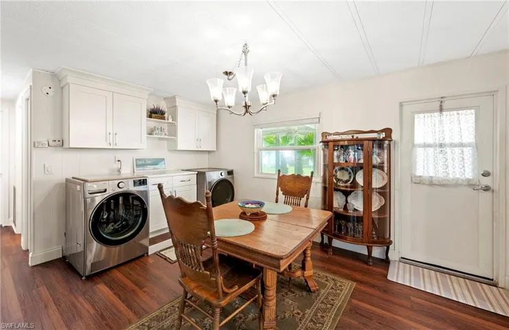 Dining space featuring a chandelier, dark wood-style floors, and washing machine and clothes dryer