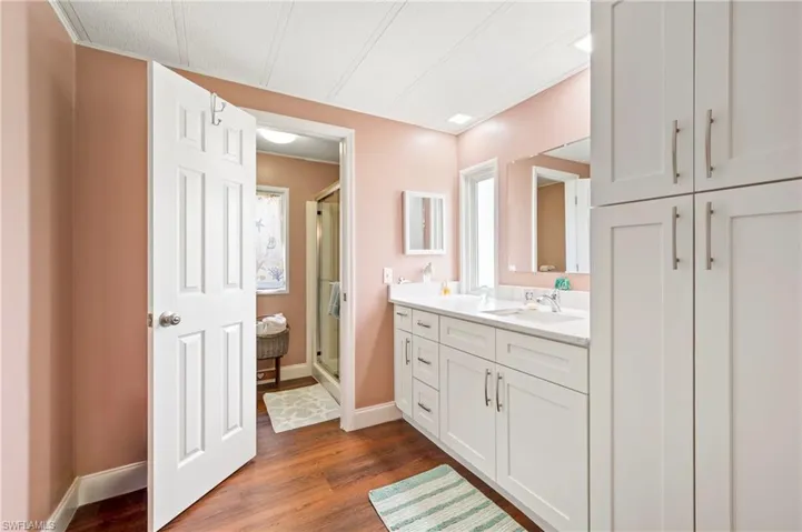 Bathroom with vanity, a stall shower, wood finished floors, and baseboards