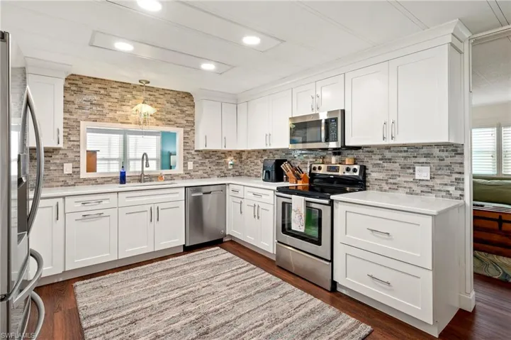 Kitchen with appliances with stainless steel finishes, a sink, backsplash, light countertops, and recessed lighting