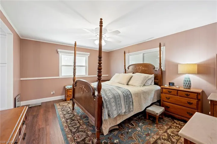 Bedroom with wood finished floors, baseboards, ceiling fan, and crown molding