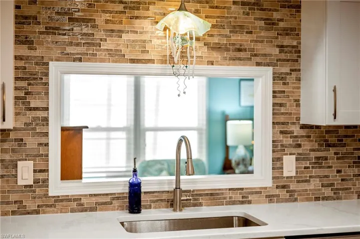Kitchen featuring a sink, light countertops, white cabinetry, and plenty of natural light