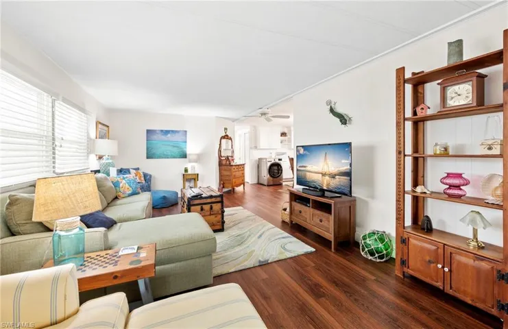 Living room with wood finished floors, washing machine and clothes dryer, and ceiling fan