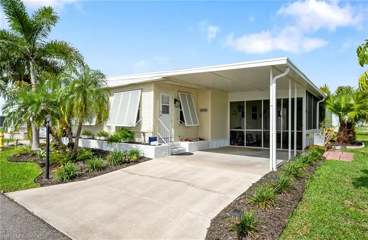 Rear view of property featuring driveway, a sunroom, and an attached carport