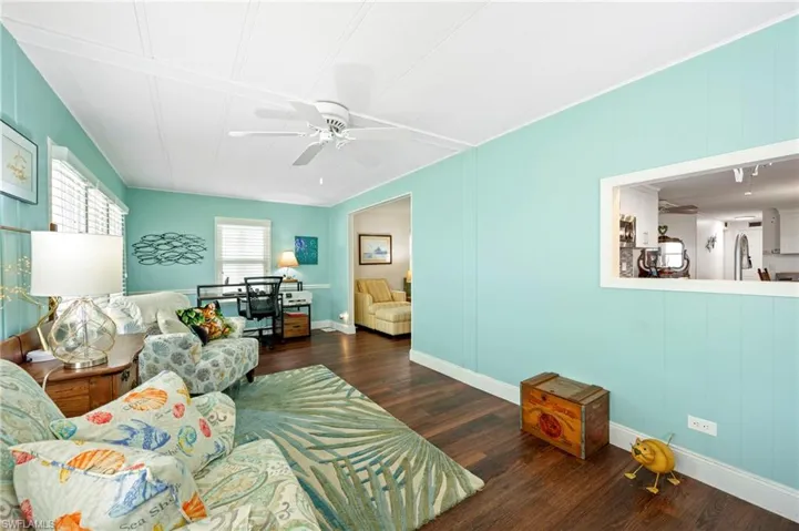 Living area with a ceiling fan, wood finished floors, and baseboards