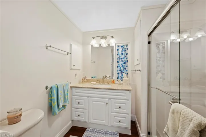Bathroom featuring vanity, a stall shower, toilet, baseboards, and wood finished floors