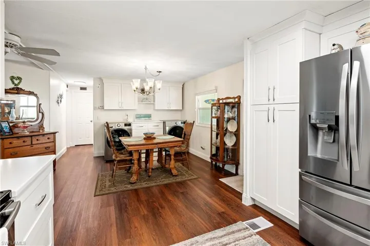 Dining space featuring dark wood-style flooring, a chandelier, a ceiling fan, and washer / clothes dryer