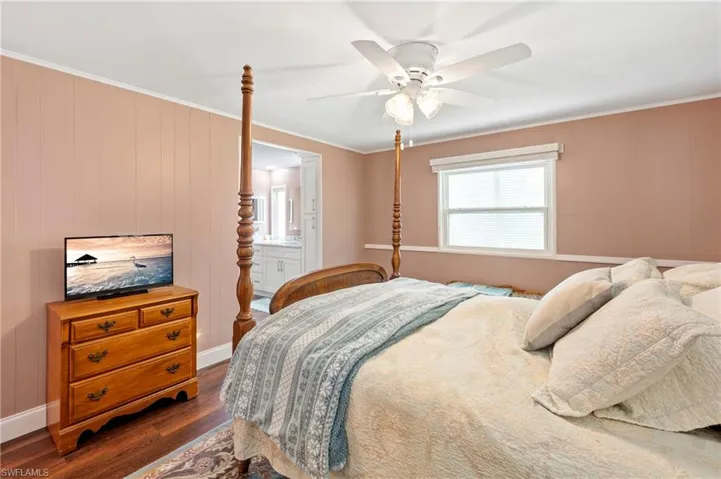 Bedroom featuring dark wood-type flooring, crown molding, a ceiling fan, and ensuite bath