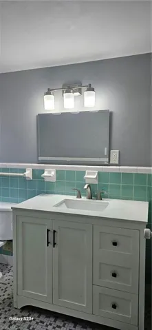 Bathroom with vanity, tile walls, a wainscoted wall, tile patterned floors, and a textured wall