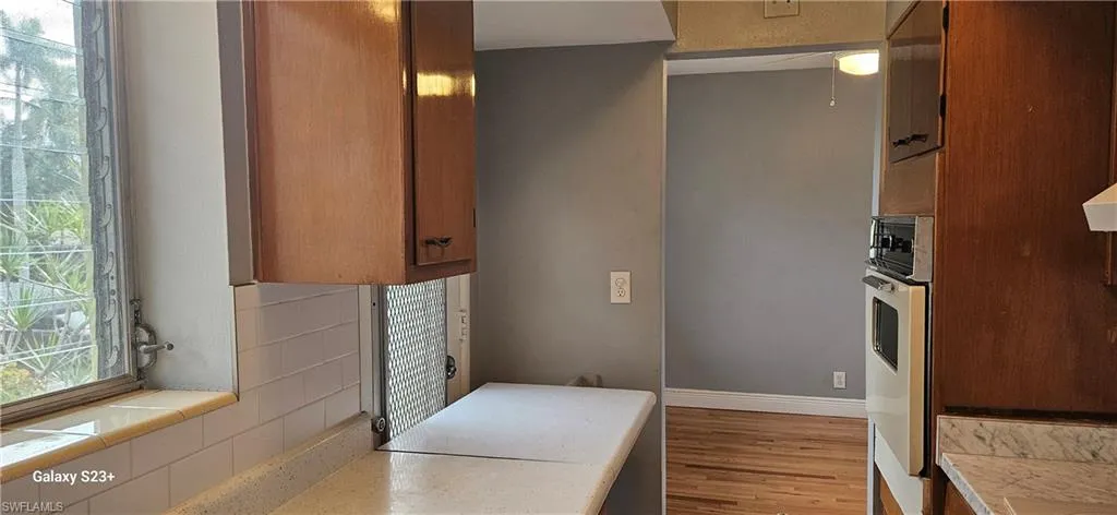 Kitchen featuring light countertops, brown cabinets, wood finished floors, and decorative backsplash