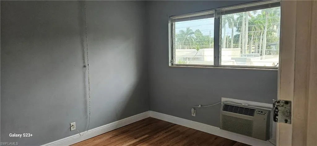 2nd bedroom with wood finished floors and a wall mounted air conditioner