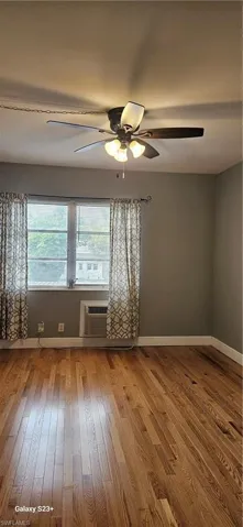 Unfurnished room featuring plenty of natural light, light wood finished floors, and an AC wall unit