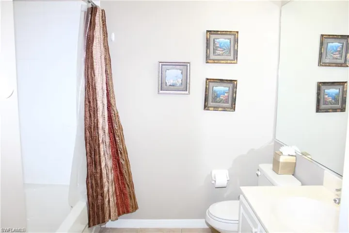 Full bathroom featuring tile patterned flooring, shower / bath combo with shower curtain, toilet, and vanity