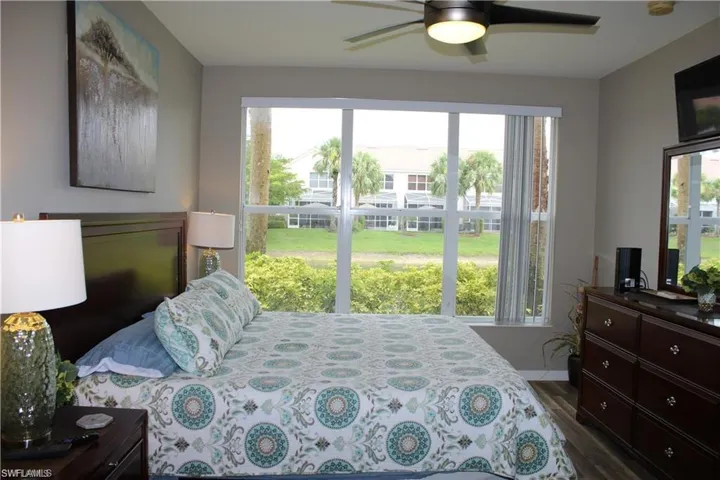 Bedroom with multiple windows, dark hardwood / wood-style flooring, and ceiling fan