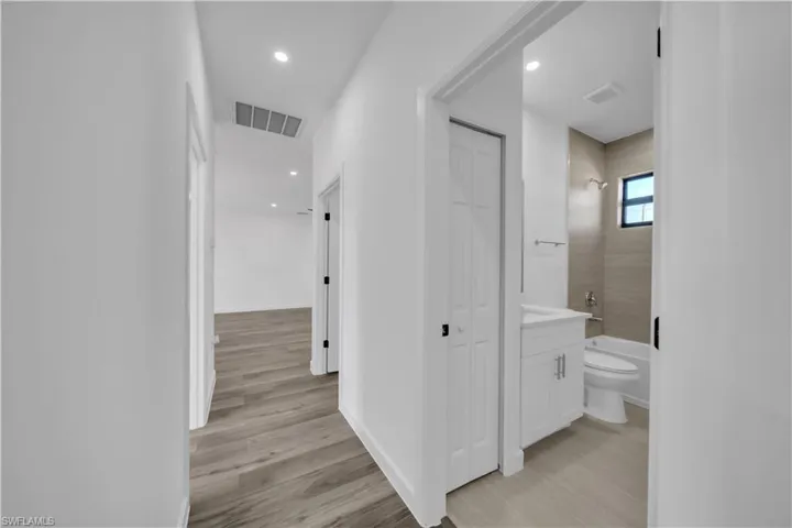 Hallway with light wood finished floors and recessed lighting