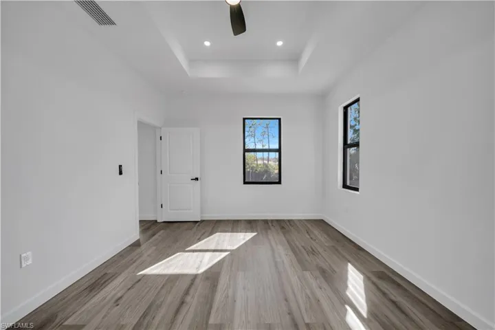 Spare room featuring ceiling fan, light wood-style floors, recessed lighting, and a tray ceiling