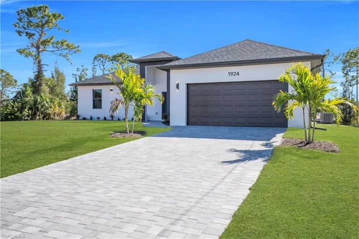 View of front of home with a front lawn, decorative driveway, stucco siding, a garage, and a shingled roof