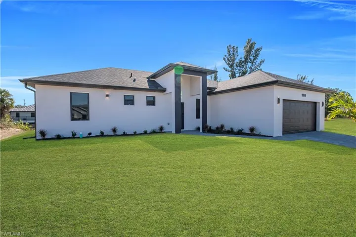 View of front facade with a front lawn, a shingled roof, driveway, and stucco siding