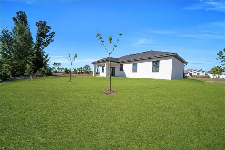 Rear view of property with a yard, stucco siding, and a patio area