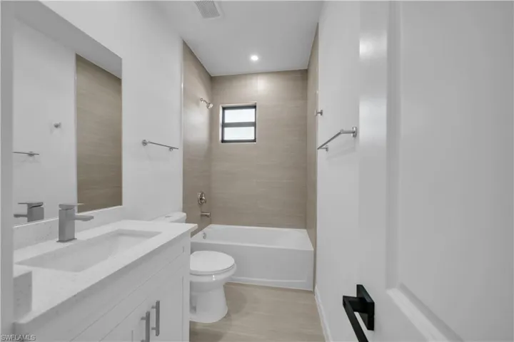 Bathroom with tub / shower combination, vanity, and light wood-type flooring