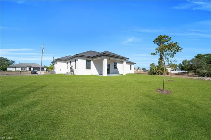 View of front of property featuring a front yard, stucco siding, and a patio area