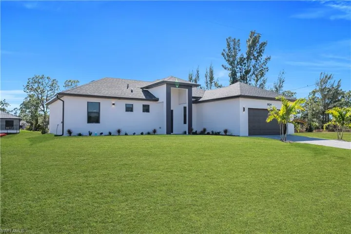 View of front facade with a front lawn, stucco siding, and a shingled roof
