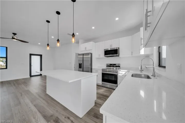 Kitchen with healthy amount of natural light, white cabinetry, stainless steel appliances, and a center island