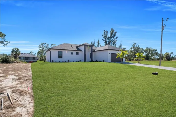 View of front of home featuring a front lawn, stucco siding, an attached garage, driveway, and a shingled roof