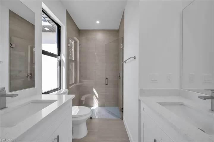 Bathroom with two vanities, a stall shower, and recessed lighting