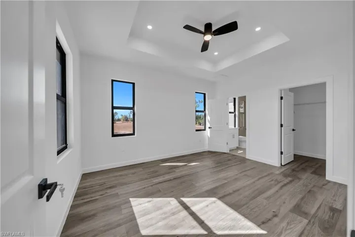Unfurnished bedroom with light wood-type flooring, a spacious closet, a ceiling fan, recessed lighting, and ensuite bathroom