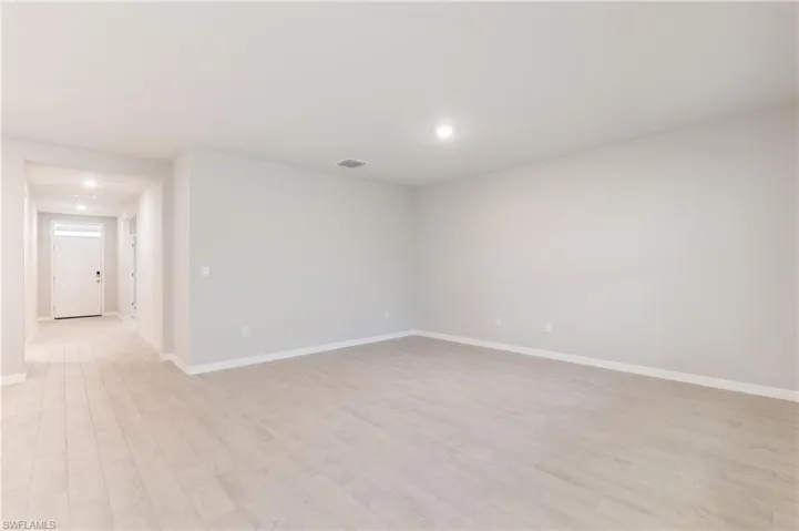 Empty room with light wood-style floors and recessed lighting
