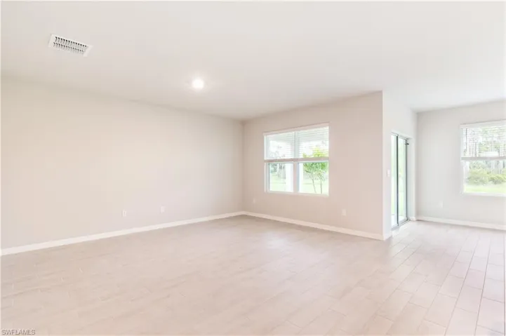 Empty room with light wood finished floors, plenty of natural light, and recessed lighting