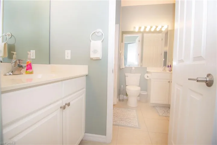Second bathroom features light tile flooring and white tub with tiled shower as well as a vanity in the main bath and a second vanity area adjacent to the second bedroom.