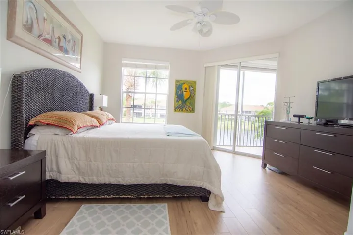 Large primary bedroom suite featuring featuring a sliding glass door to the screened lanai, LVP floors, a ceiling fan, 2 walk in closets and plenty of room for even the largest furniture configurations.