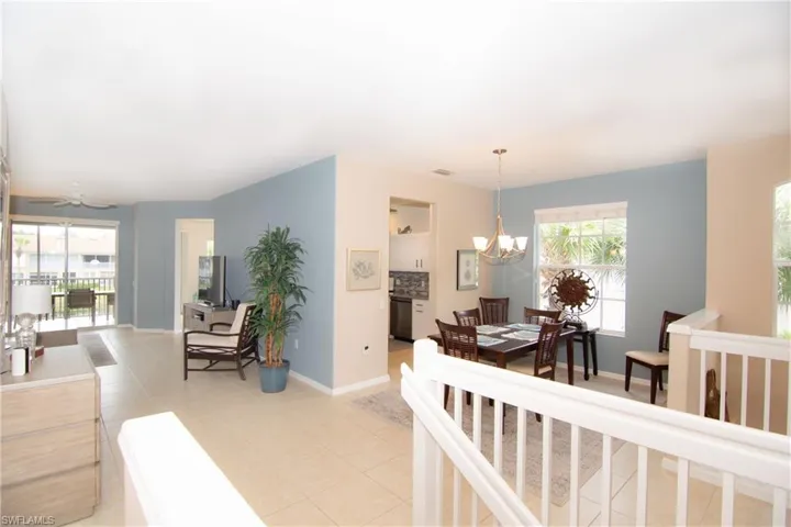 Tastefully furnished living room with ceiling fan and light tile floors with telescoping sliding doors to the screened lanai.