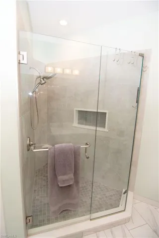 Custom tiled shower with a shower with frameless glass door.