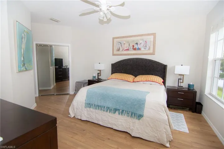 Large primary bedroom suite featuring featuring a sliding glass door to the screened lanai, LVP floors, a ceiling fan, 2 walk in closets and plenty of room for even the largest furniture configurations.