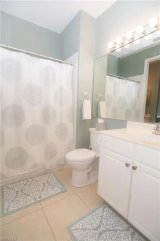 Second bathroom features light tile flooring and white tub with tiled shower as well as a vanity in the main bath and a second vanity area adjacent to the second bedroom.