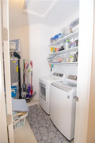 In unit utility room features oversized capacity washer and clothes dryer, extra shelf storage, tile floors,  and electric water heater and electrical panel.