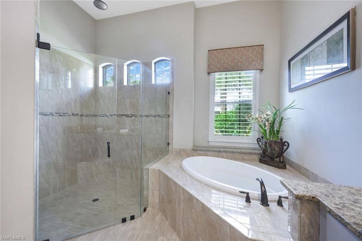 Master bathroom features a walk-in shower with frameless glass and soaking tub.