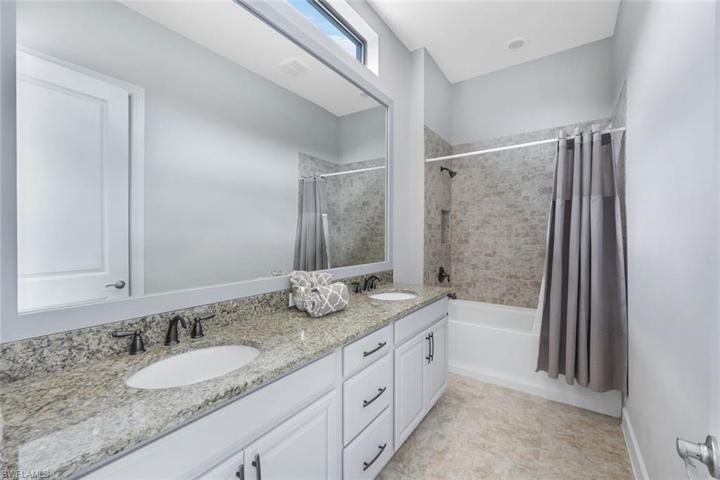 Note the dual sinks in this ensuite bathroom, and shower/tub combo with decorative tile.